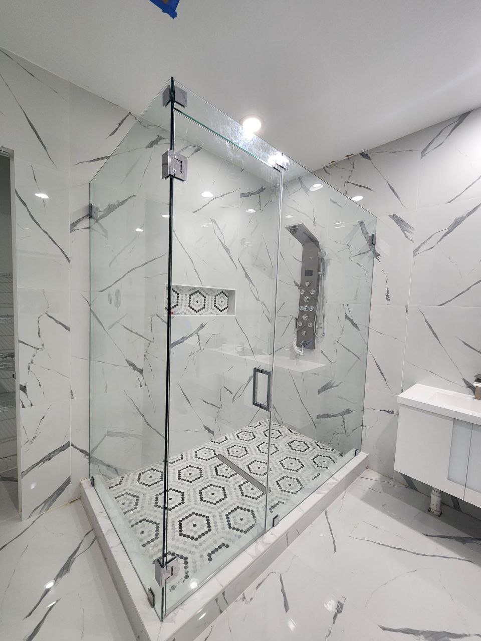 Frameless glass shower enclosure, black marble bathroom