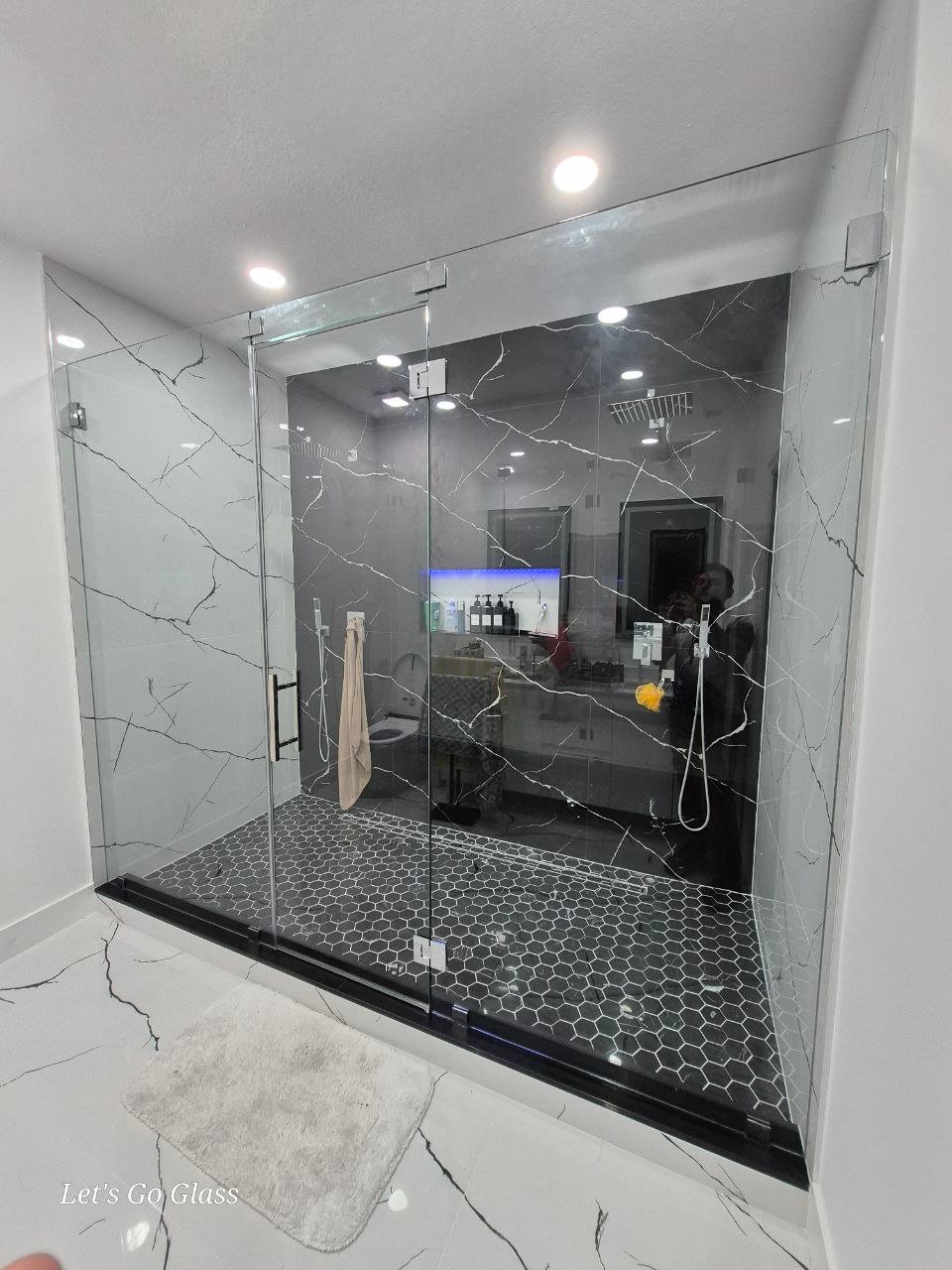 Frameless glass shower door, dark marble bathroom